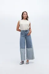 Jean wide leg de tiro alto, confeccionado en denim de algodón. Presenta un diseño bicolor con paneles en dos tonos de azul claro, creando un efecto de patchwork en la parte inferior de las piernas.