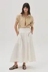 Falda larga color blanco tiza, de corte evasé, con cintura alta y calados en el ruedo con detalles en lurex.