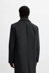 Abrigo negro regular fit confeccionado en paño con lana. Tiene cuello con solapas de muesca, manga larga, bolsillos de solapa en la cadera, bolsillo interior, abertura en el centro de la espalda y cierre frontal con botonadura.