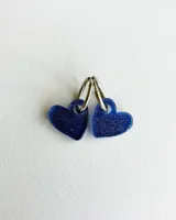 Par de aros colgantes con forma de corazón azul con glitter y argolla plateada.