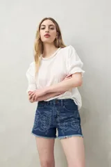 Short de jean azul con bordado floral en el frente y ruedo desflecado.