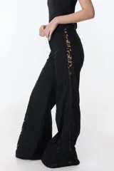 Pantalón de jean negro de pierna ancha con cortes en los laterales que van desde la pretina al bajo del pantalón. Por la mitad de la pierna presenta godets triangulares de encaje para darle mayor amplitud y detalles a la prenda.