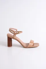 Sandalia de cuero color nude con pulsera al tobillo y taco cilíndrico de madera.