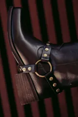 Bota corta de cuero color marrón oscuro, con hebilla dorada y arnés desmontable.