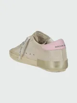 Championes Golden Goose modelo Super Star, color beige con detalles en rosa y estrella con estampado animal print. Cordones con texto y efecto desgastado en la suela.