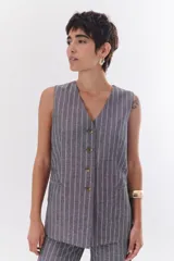 Chaleco gris con finas rayas verticales blancas, con cuello en V, cierre frontal con botones y bolsillos laterales.