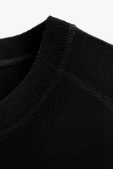Remera blanca de punto liso, corte amplio, cuello redondo y manga corta.
