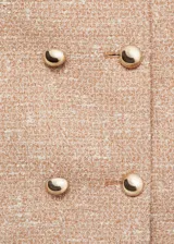 Chaqueta corta de tweed color rosa pálido con doble botonadura dorada, cuello redondo y bolsillos de parche en el pecho.