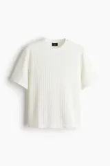 Remera blanca de punto calado con textura tipo crochet, corte estándar, cuello redondo y mangas cortas.