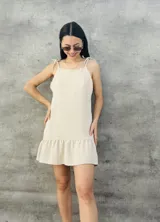 Vestido corto de color beige con tirantes tipo halter y falda con volado.