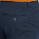 Pantalón chino de sarga azul marino, corte slim, con bolsillos laterales y traseros. Cierre con botón y cremallera.
