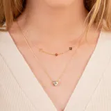 Set de dos gargantillas de oro amarillo 18k. Una con dije de corazón con circonia y otra con dijes de flores.