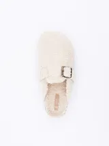 Pantuflas cerradas color crema, forradas en piel sintética con hebilla decorativa.