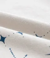 Remera color beige de corte alargado, cuello redondo y mangas cortas. Estampado frontal con una mariposa azul rodeada de elementos celestiales.