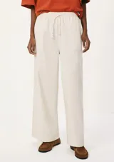 Pantalón de lino color crema, de corte recto y tiro alto, con cintura elástica ajustable con cordón y bolsillos laterales.
