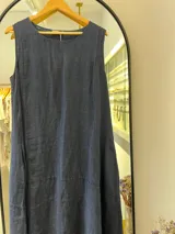 Vestido sin mangas, azul marino, con escote redondo y corte amplio que cae en línea A. Presenta costuras verticales y un corte horizontal a la altura de la cadera que añade estructura al diseño.