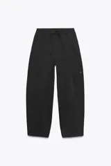 Pantalón cargo negro de corte amplio con cintura ajustable con cordón, bolsillos laterales y bolsillos tipo parche en las piernas.