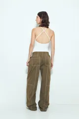 Pantalón tipo babucha negro de tiro bajo con costuras visibles en contraste blanco. Presenta cintura elástica con lazo ajustable blanco y silueta amplia con caída relajada.