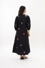 Vestido midi color arena con escote en V, mangas 3/4 abullonadas y cierre frontal con botones. Presenta bordados de motivos marinos.