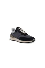 Zapatilla deportiva de hombre con diseño retro, combinando paneles de cuero negro, gamuza negra y detalles en gris claro en el cuello y talón. La suela es gruesa y de color beige claro con una banda de rodadura negra. Los cordones son de color crema.