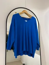 Sweater azul francia de corte recto, con cuello en pico y punto elástico en los puños.