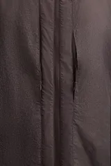 Cazadora con capucha confeccionada en tejido técnico ligero con partículas reflectantes. Cuenta con cuello alto, mangas largas con puños elásticos, bolsillos frontales con cierre de cremallera y cierre frontal con cremallera.