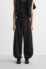 Pantalón de jogging negro, corte balloon fit, con cintura elástica ajustable con cordón, bolsillos laterales y trasero, costura frontal en las perneras y puños elásticos en los tobillos.
