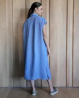 Túnica celeste de corte recto, con cuello camisero, mangas cortas, tajos laterales y cierre frontal con botones.