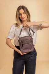 Morral bandolera color lila con correa ajustable, dos bolsillos frontales con cierre y dos bolsillos internos.