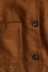 Chaqueta marrón de tejido suave con acabado cepillado, cuello redondo, cierre de botones adelante y bolsillos parche delanteros.