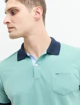 Remera polo blanca de piqué con cuello y puños en azul marino. Tiene tapeta de dos botones y bolsillo de parche en el pecho.