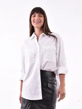 Camisa blanca de mangas largas con bolsillos frontales con detalle de calado. Corte clásico y cierre con botones.