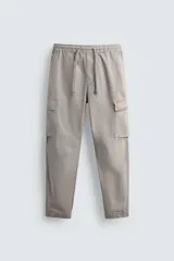 Pantalón cargo slim fit negro con cintura elástica ajustable con cordón, bolsillos frontales, traseros y laterales con solapa. Bajo con puño elástico.