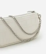Cartera baguette color blanco con textura croco, asa corta de cadena plateada y cierre de cremallera.