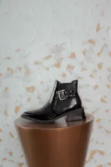 Botines Chelsea color beige con elásticos laterales negros, punta cuadrada, detalle de hebilla lateral y tacón bloque bajo.