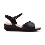 Sandalia de cuero sintético color negro, con plataforma baja y tira con hebilla dorada en el tobillo.