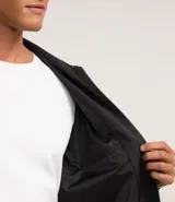 Campera negra de algodón con cuello inglés, cierre con cremallera, manga larga con ajuste fruncido elástico en el bajo trasero y bolsillos laterales.