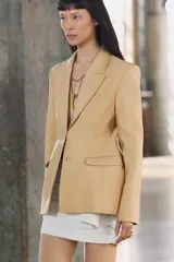 Blazer amplio color dorado confeccionado en hilatura con viscosa. Cuello solapa de muescas y manga larga. Bolsillos con solapa en delantero y de vivo en pecho. Forro interior. Cierre frontal con botones.