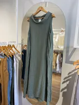 Vestido largo de lino color celeste, sin mangas y con cuello buche. Presenta un diseño de corte holgado con bolsillos laterales.