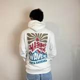 Canguro blanco con capucha y cordones ajustables. Estampado en la espalda con un sol marrón, texto en rojo y azul que dice "Chasing the waves Santa Barbara".
