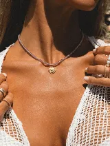 Collar corto de cristalitos facetados color lila con dije dorado en forma de sol.