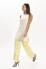Pantalón palazzo de tejido de punto color amarillo con estampado de hojas blancas.