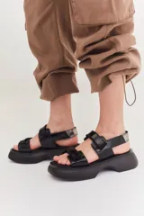 Sandalias negras con plataforma, tiras anchas con ajuste de velcro y detalle plateado en el talón.