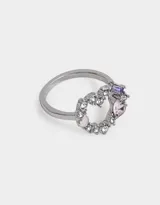Anillo plateado con forma de corazón, adornado con strass blancos y gemas rosas y violetas.