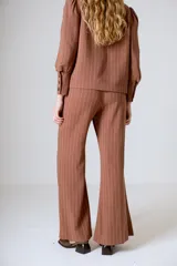 Pantalón de lino color beige, corte flare, tiro medio y costuras verticales al frente.