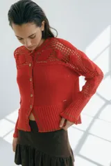 Cárdigan azul con detalles en crochet, mangas con volado y vivos de color rojo en cuello, puños y frente. Tiene botones al frente.