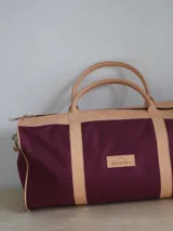 Bolso de lona color negro con detalles en cuero color tostado. Tiene doble asa de mano y correa de hombro ajustable y extraíble.