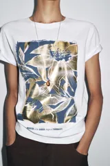 Camiseta blanca de algodón con cuello redondo, manga corta y estampado metalizado en el frente con formas abstractas y texto "AILGN92 SHAPES OF HARMONY".