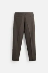 Pantalón de vestir color marrón oscuro, confeccionado en lino italiano. Presenta corte regular fit, cintura con pliegues, bolsillos laterales y traseros ribeteados, y terminación con dobladillo. Cierre frontal con cremallera y botón.