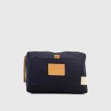 Neceser rectangular de lona color azul marino con detalles en cuero color suela. Tiene un bolsillo frontal con cierre y un asa lateral de cuero.